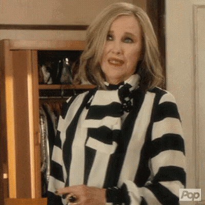 Woman In Striped Shirt Holding Wine In Front Of Closet GIF