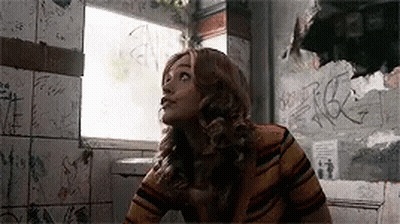 Woman in Striped Shirt in Bathroom With Graffiti