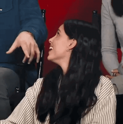 Woman In Striped Shirt Laughing While Man Points GIF