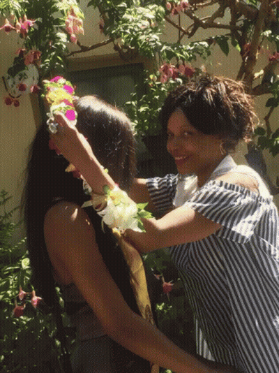 Woman In Striped Shirt Putting Flowers On Another Woman's Head GIF