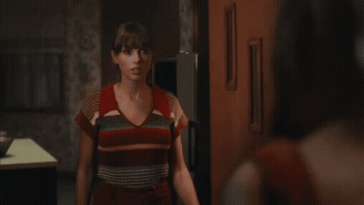 Woman In Striped Shirt Saying Hi In Dark Room GIF