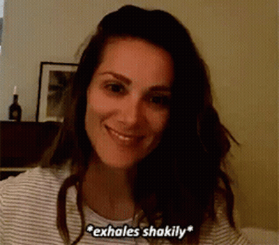 Woman In Striped Shirt Smiling And Exhaling Shakily GIF