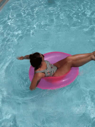 Woman In Striped Swimsuit On Pink Float GIF