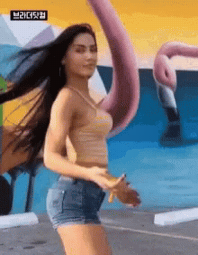 Woman In Striped Tank Top And Shorts In Front Of Flamingo Mural GIF