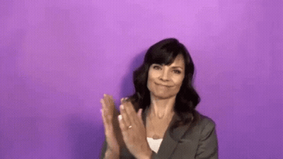 Woman In Suit Clapping In Front Of Purple Wall GIF