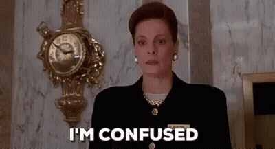 Woman In Suit Confused In Front Of Clock GIF