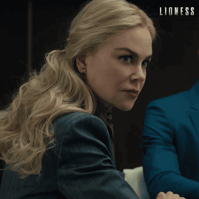 Woman In Suit Sitting Next To Man In Blue Suit Saying Lioness GIF
