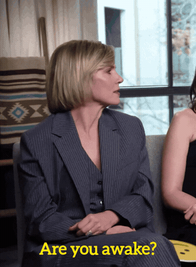 Woman In Suit Sitting On Couch GIF