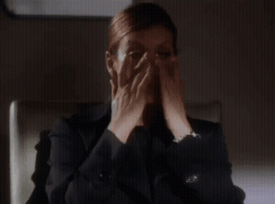 Woman In Suit Sitting With Hands Up GIF