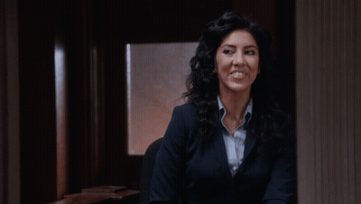 Woman In Suit Smiling In Dark Room GIF