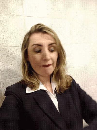 Woman In Suit Standing Before Tiled Wall GIF