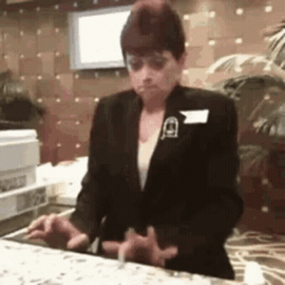 Woman In Suit Standing Behind Counter GIF