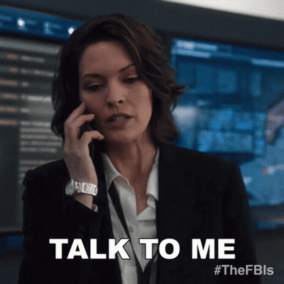 Woman In Suit Talking On Phone Saying Talk To Me GIF