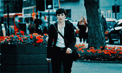 Woman In Suit Walking Down Street With Flowers GIF