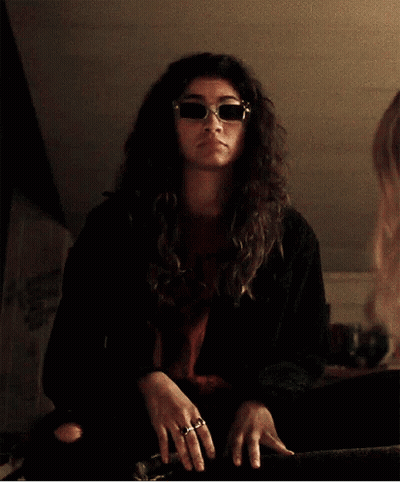 Woman In Sunglasses And Black Jacket Gesturing At Mirror GIF