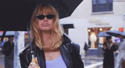 Woman In Sunglasses And Black Jacket Holding Umbrella In Rain GIF