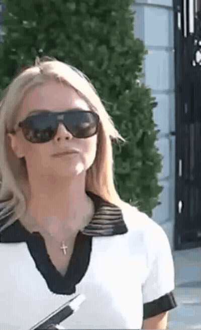 Woman In Sunglasses And Cross Necklace In Front Of Building GIF