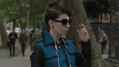 Woman In Sunglasses And Earbuds Walking GIF
