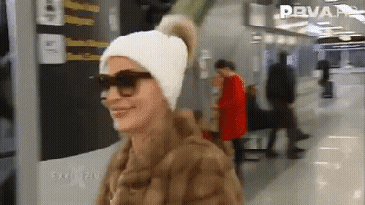 Woman In Sunglasses And Fur Coat Smiling In Front Of Prvar Sign GIF
