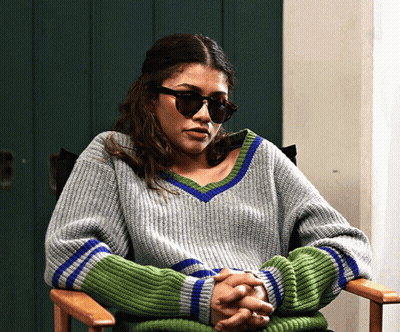 Woman In Sunglasses And Grey Green Sweater Sitting GIF