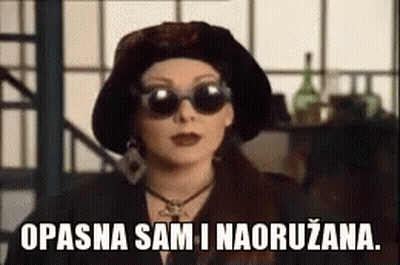 Woman In Sunglasses And Hat Saying Opasna Sam I Naoruzana GIF