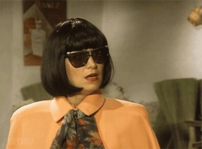 Woman In Sunglasses And Wig In Front Of Lotion Sign GIF