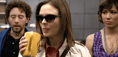 Woman In Sunglasses Holding Yellow Object GIF