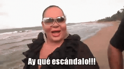 Woman In Sunglasses On Beach Saying Ay Que Escandalo GIF