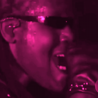 Woman In Sunglasses Singing Into Microphone In Dark Room GIF