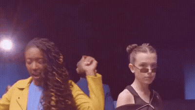 Woman In Sunglasses Standing In Dark Room With Group GIF