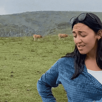 Woman in Sunglasses Standing in Field With Cows