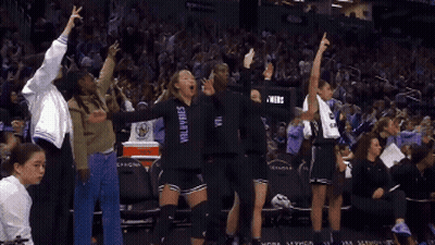 Woman In Superhero Costume Holding Blue Flag Next To Machine GIF
