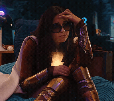 Woman In Superhero Costume Sitting On Bed Hand On Head GIF
