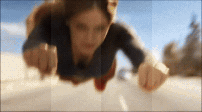 Woman In Superman Costume Flying Over Road GIF