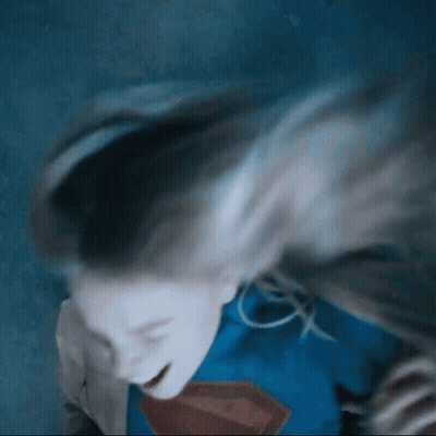 Woman In Superman Costume Laying Down Hair Blowing GIF