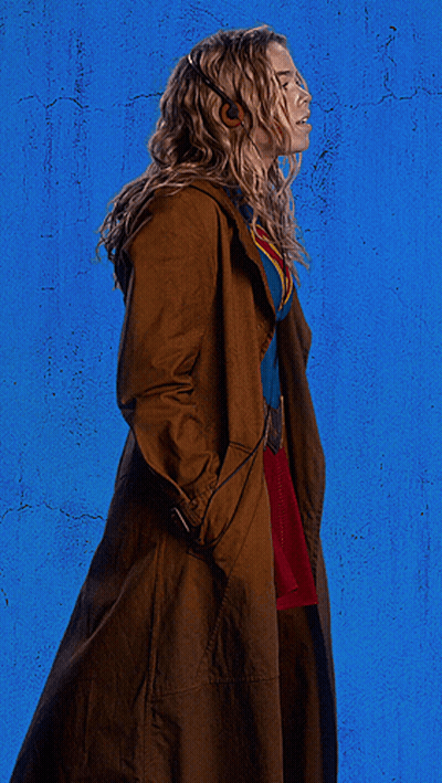 Woman In Superman Costume With Headphones And Trench Coat GIF