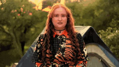 Woman In Tiger Print Shirt In Front Of Tent GIF