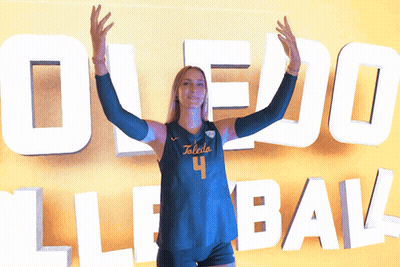 Woman In Toledo 4 Jersey Stands In Front Of Large Sign GIF