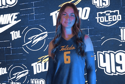 Woman In Toledo 6 Jersey In Front Of Logo Wall GIF