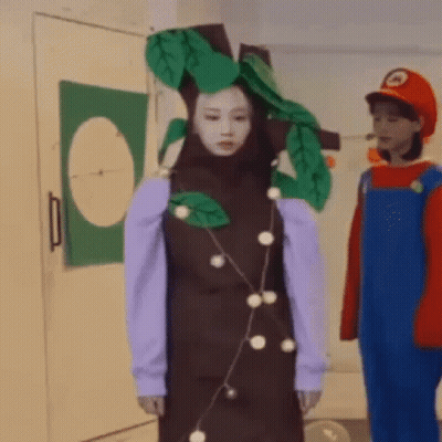 Woman In Tree Costume Next To Man In Mario Costume GIF