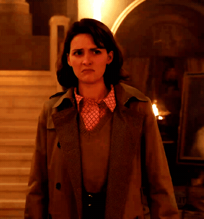 Woman In Trench Coat And Pink Shirt In Dark Room GIF