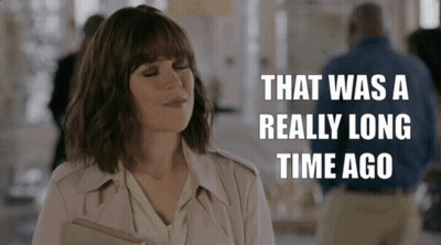 Woman In Trench Coat Holding Book Says That Was A Really Long Time Ago GIF