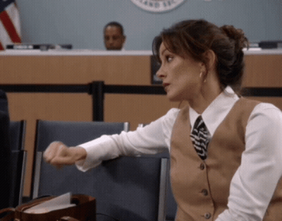 Woman In Vest And Tie Sitting In Front Of County Sign GIF