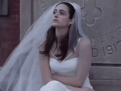 Woman In Wedding Dress Sitting In Front Of Stone Wall Saying Give Peace GIF