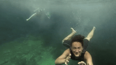Woman In Wetsuit Swimming And Waving GIF