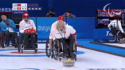 Woman In Wheelchair Throws Stone In Front Of Beijing Sign GIF