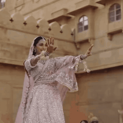 Woman In White And Silver Dress Dancing In Front Of Building GIF