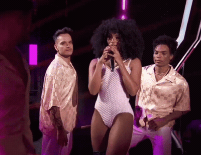 Woman In White Bodysuit Singing Into Microphone GIF