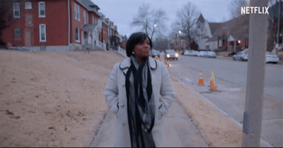 Woman In White Coat Walking Down Sidewalk With Netflix Logo GIF