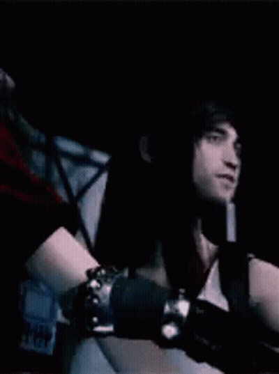 Woman In White Dress And Red Jacket Standing Next To Man In Dark Room GIF